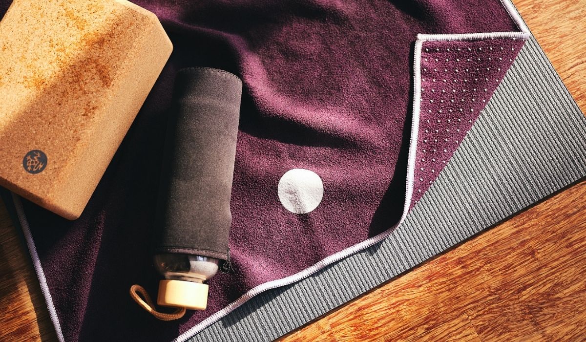 Purple hot yoga towel with a cork block and water bottle on it.