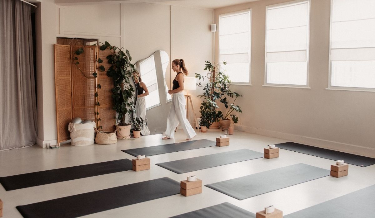 A serene yoga studio with several mats arranged neatly, surrounded by plants and soft natural light filtering through the windows.