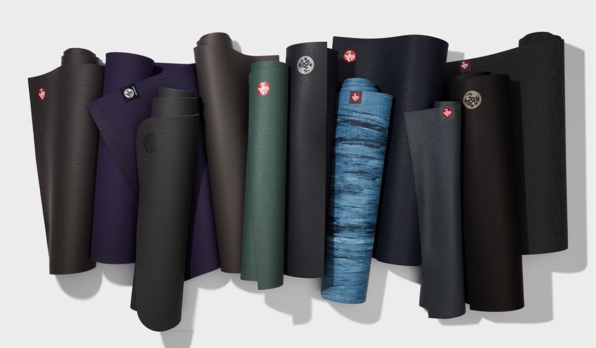 A collection of various yoga mats, rolled and displayed in different colors, including dark shades and a blue gradient.