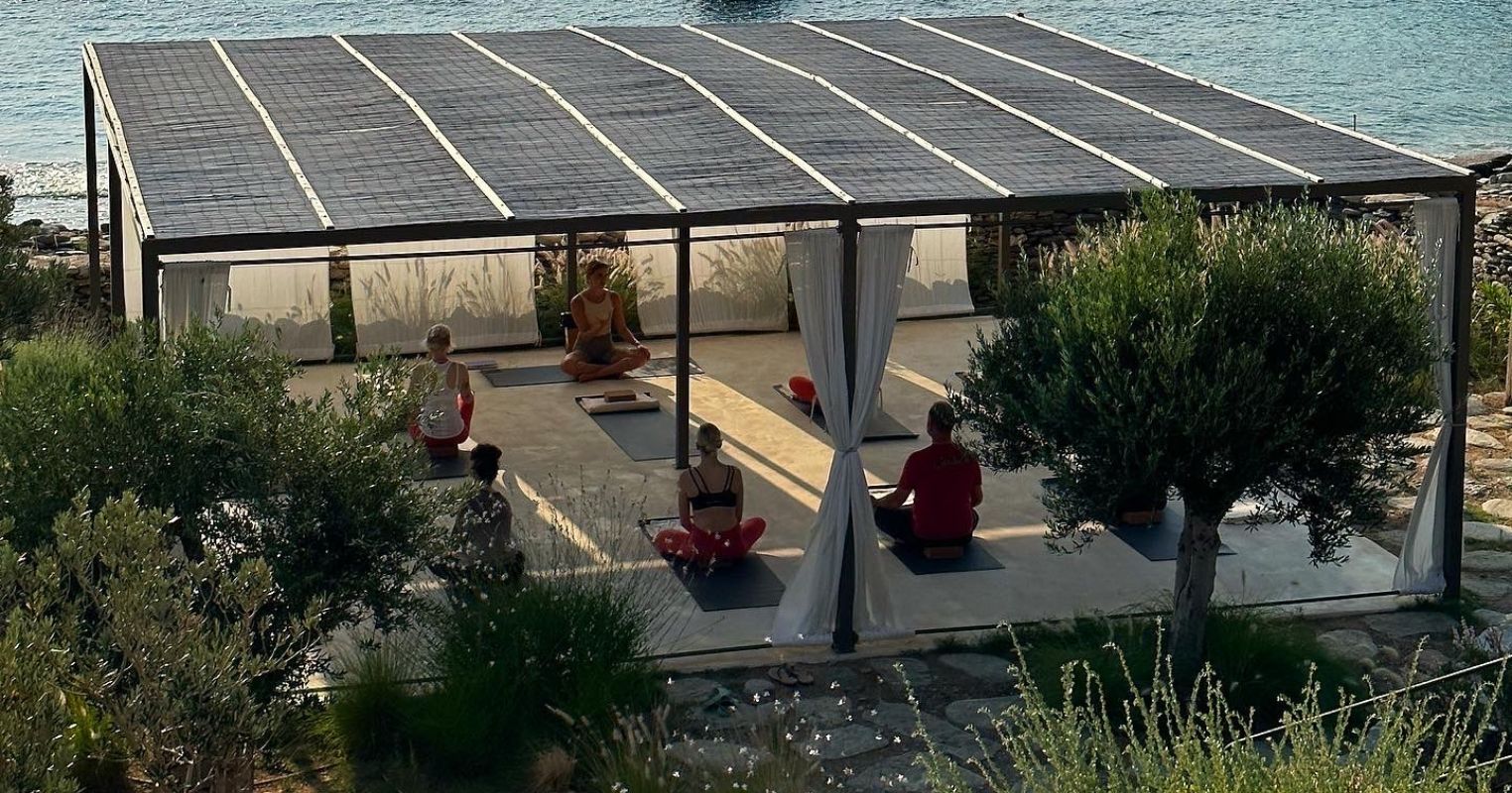 A serene outdoor yoga session under a solar-paneled roof, with participants practicing mindfulness by the water's edge.