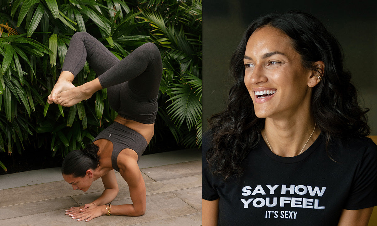 A woman performs a yoga pose, balancing on her hands with legs raised, surrounded by lush green foliage.