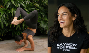 A woman performs a yoga pose, balancing on her hands with legs raised, surrounded by lush green foliage.