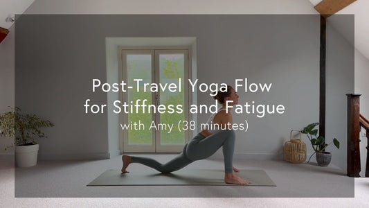 Woman in yoga pose on mat in bright, minimalist room with plants, preparing for a post-travel yoga flow session.