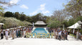 A large group of people stands beside a pool, with a decorative 